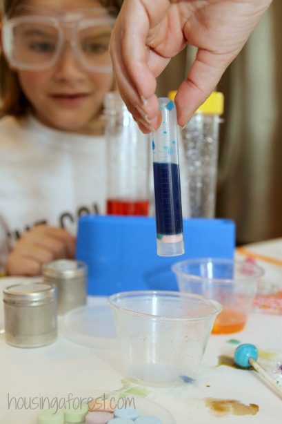 young girl with science glasses looking at vials of candy potions