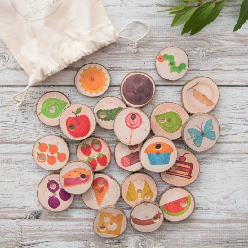 Several round wooden discs have pictures of a caterpillar and fruits on them. 
