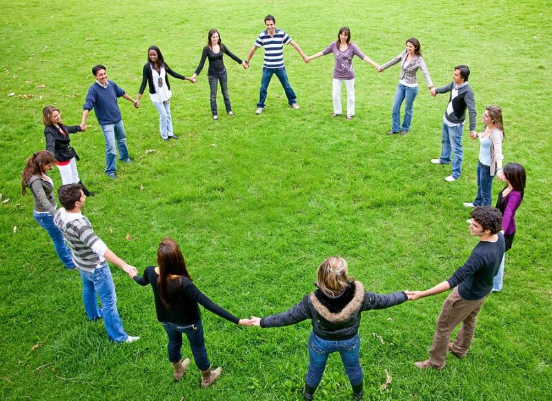 Teens standing in a circle on the grass, holding hands as an example of Pi Day activities