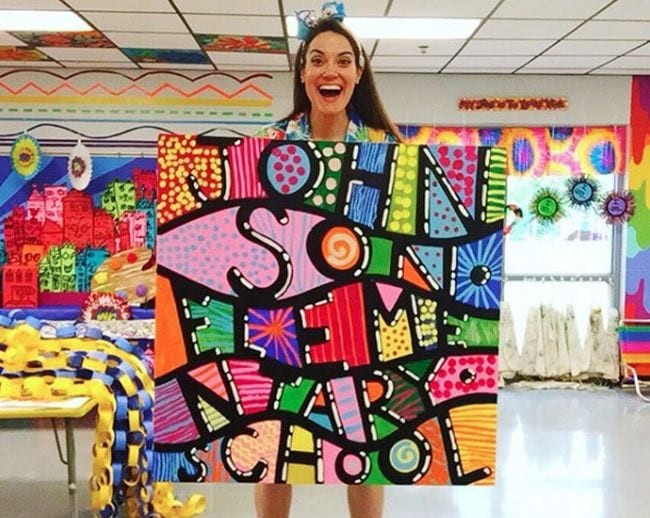 Woman holding a colorful mural poster lettered with Johnson Elementary School with patterns between the letters