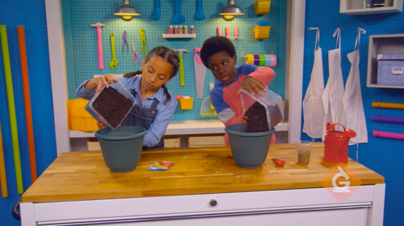 Two schoolchildren pouring dirt into pots at a worktable (Plant Life Cycle Activities) 