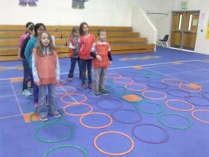 circles are laid out on the ground and students stand in two lines behind them (elementary PE games)