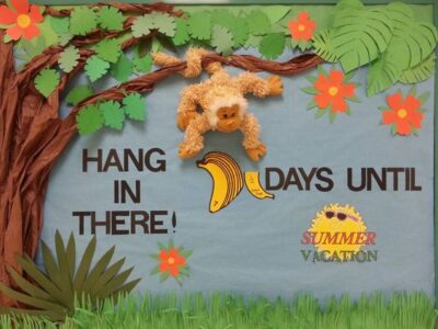Bulletin board that reads 'hang in there, 7 days until summer vacation.' There is a tree with foliage and a monkey hanging down. The number 7 is bunch of bananas with interchangeable numbers. 