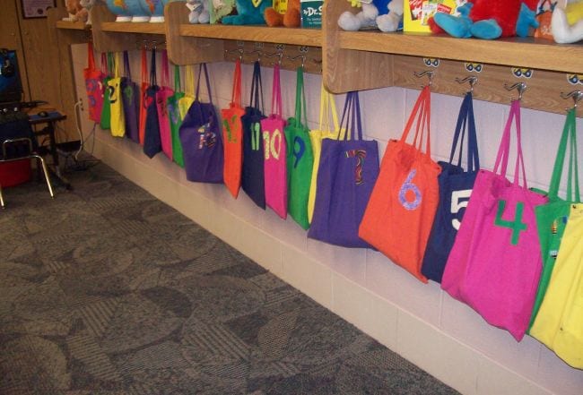 Colorful numbered tote bags hung on hooks and used as classroom storage