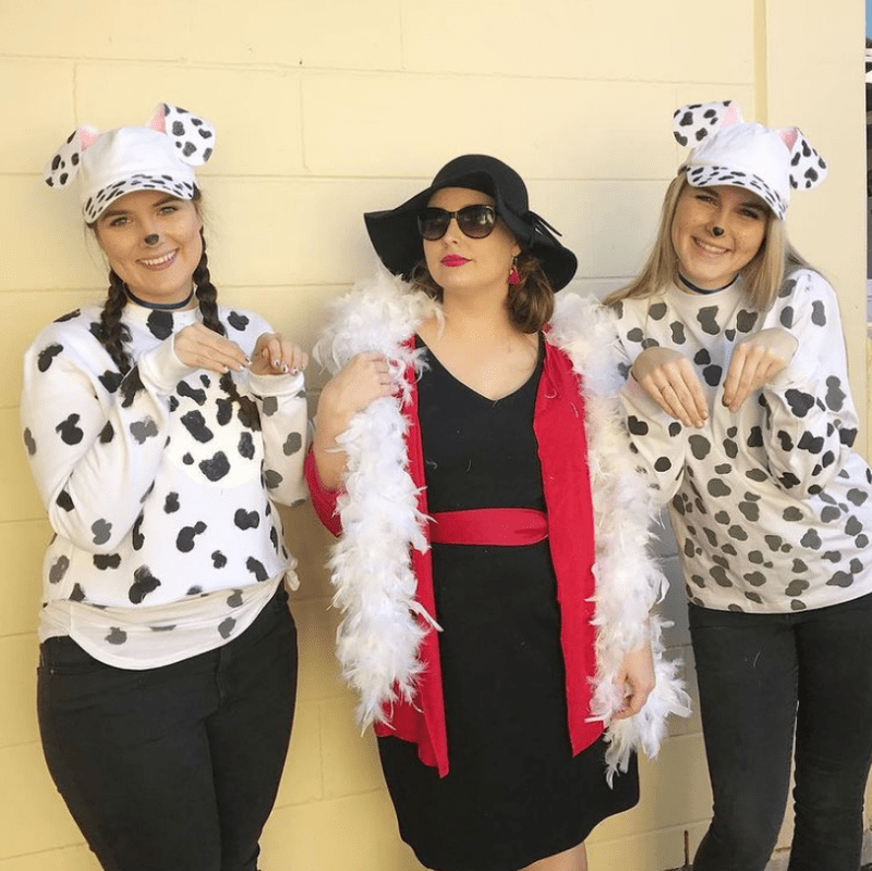Three women are shown. The two on the outsides are dressed as dalmations. The one in the middle is dressed as Cruella Deville.