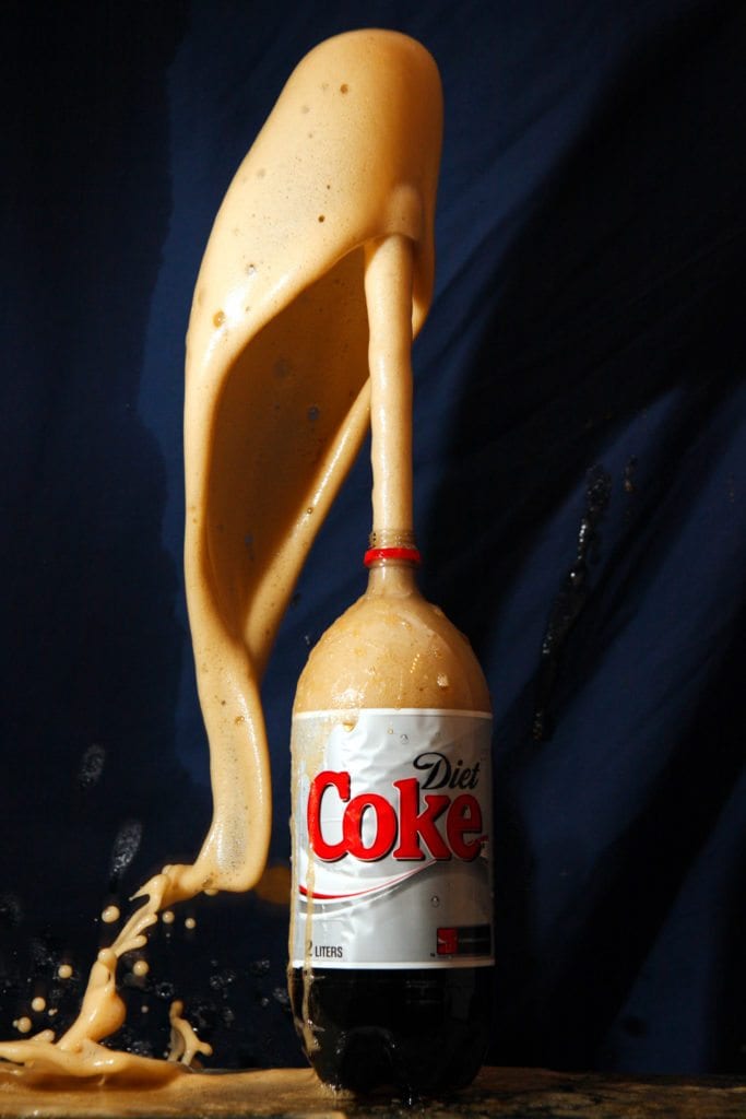 a liter bottle of Diet Coke with a geyser of soda erupting from the top