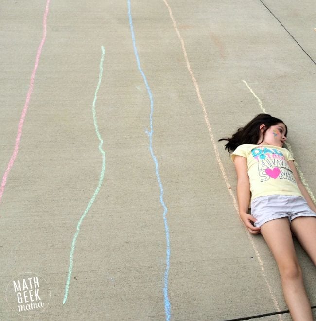 Girl laying down on sidewalk next to chalk lines