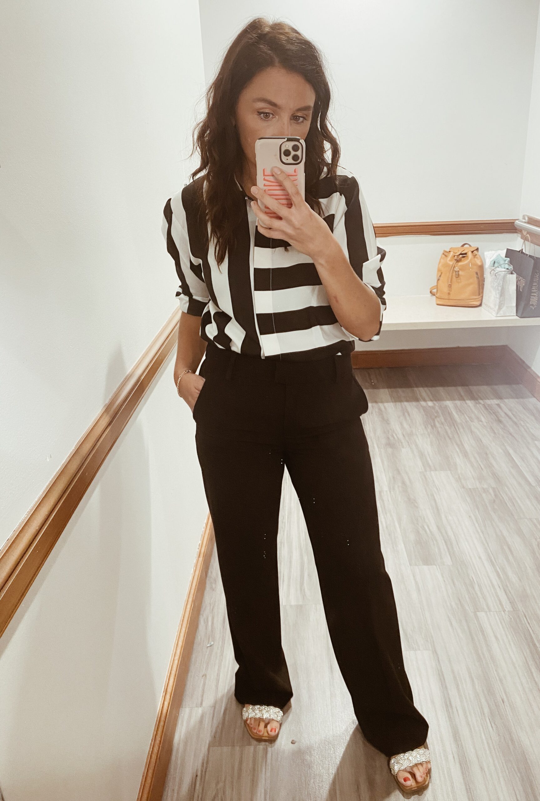 Woman in mirror wearing black and white striped shirt and black pants as an example of cute teacher outfits