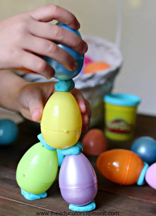 hand building a sculpture with play doh and plastic eggs 