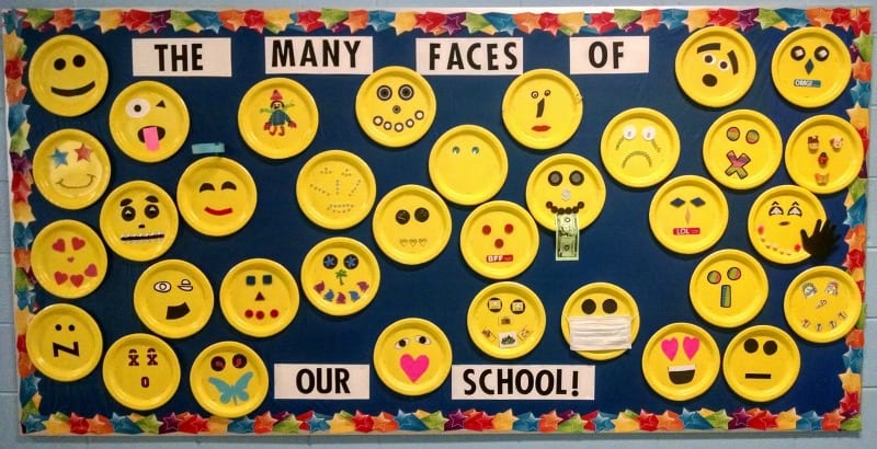 The Many Faces of Our School bulletin board, with yellow paper plates used to make emojis.