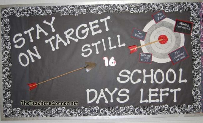 A black bulletin board has white writing that says Stay on Target Still 16 school days left. It has a target and arrows on it. 