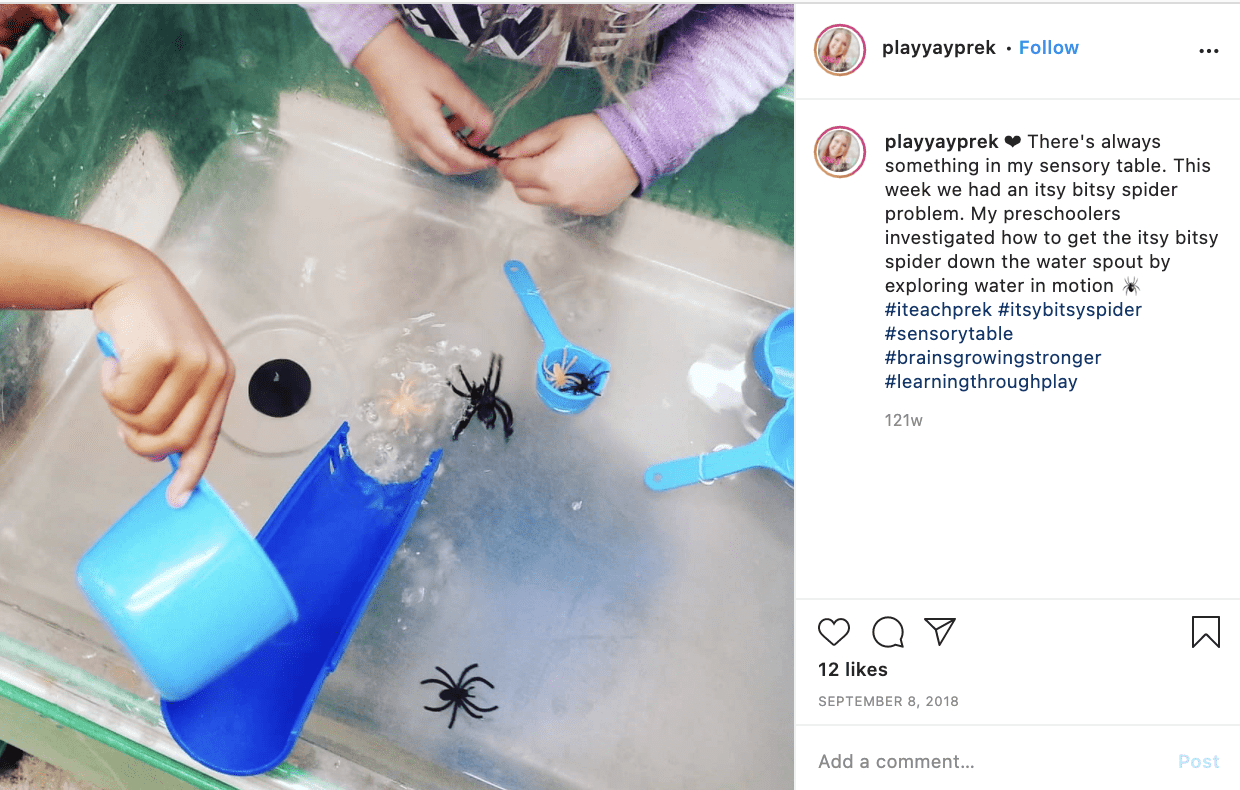 A picture of students playing with a water table that has fake spiders, a plastic spout, and measuring cups in it.