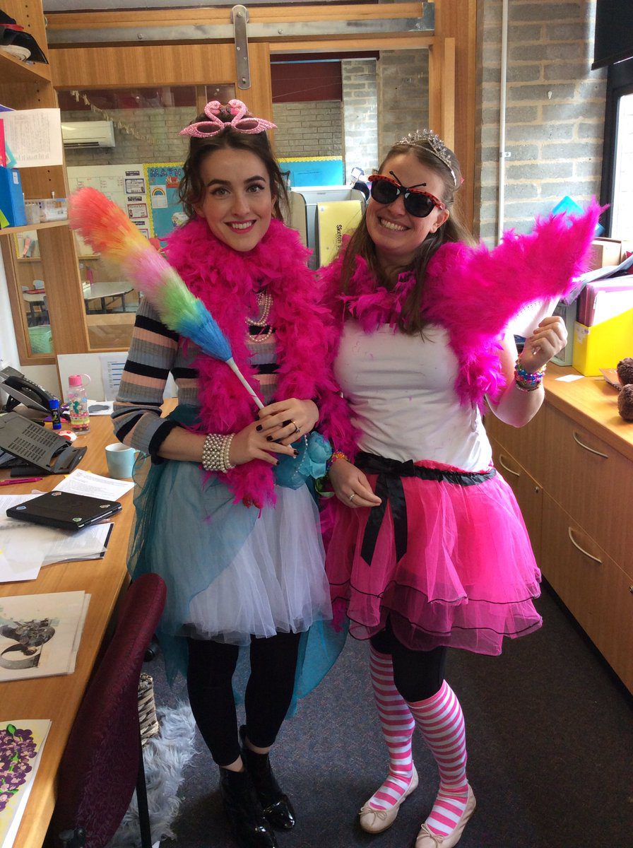 Two Women are pictured wearing a white and a pink tutu. Both have hot pink feather boas. One is holding a rainbow duster and wearing a pink crown.- book character costume