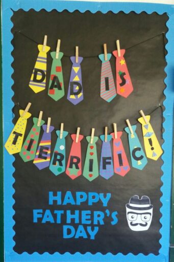 Bulletin board saying 'Dad is tierrific! Happy Father's Day.' Each letter of the words in dad is tierrific are written on different patterned ties hanging on a clothespin. 