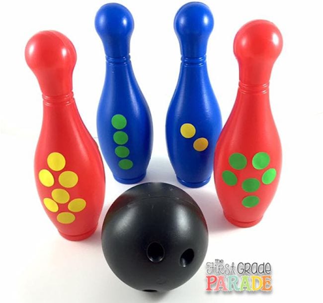 Red and blue bowling pins with dot stickers and a plastic bowling ball, used for first grade math games