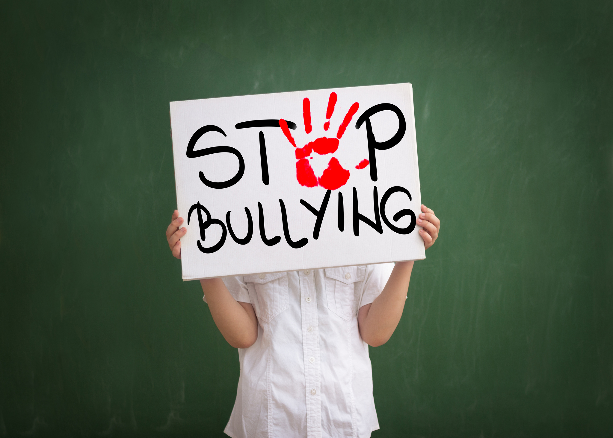 Boy holding a sign with red palm print and text stop bullying