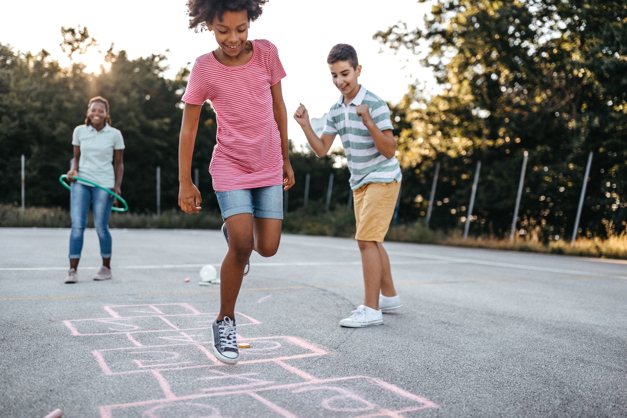 Multi-ethnic group of kids playing hopscotch outside, jumping and having fun