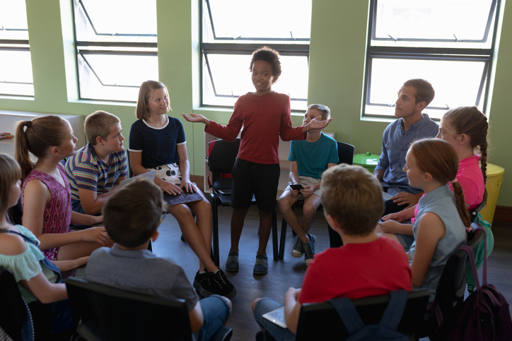 Name games can include a group of upper elementary students sitting in a circle with one student standing like the ones shown.
