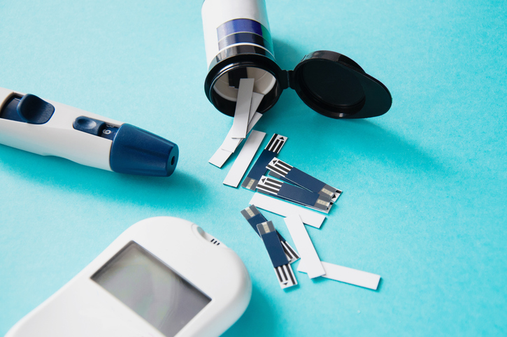 Diabetes. Glucometer. A device for measuring blood sugar levels. Test strips on a blue background. Prevention of diabetes, the concept of health and a healthy lifestyle.