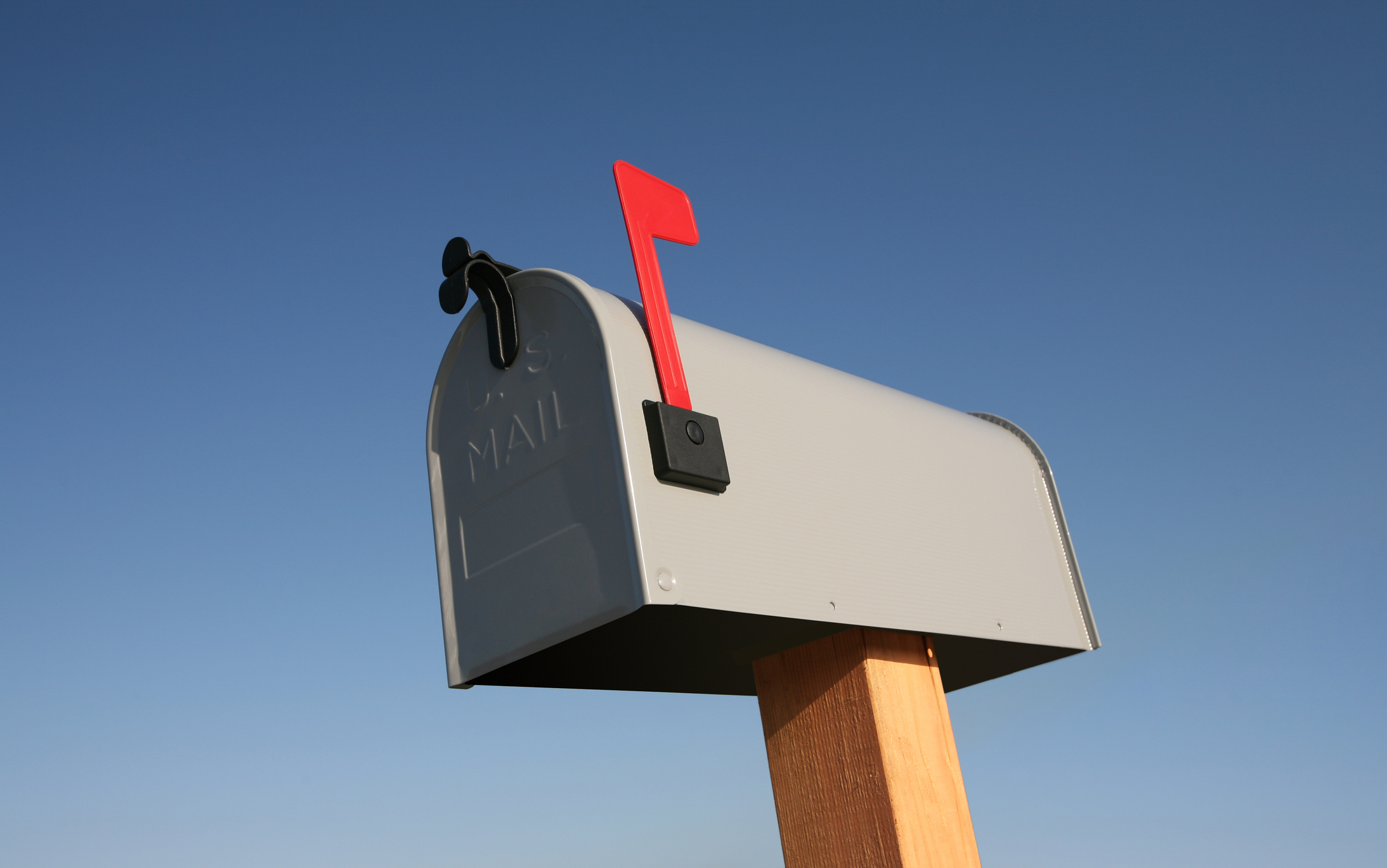 Gray mailbox with flag up against a blue sky