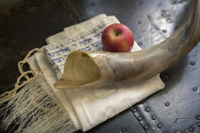 Close up of shofar ,Hebrew prayer book and apple on a table- symbols for