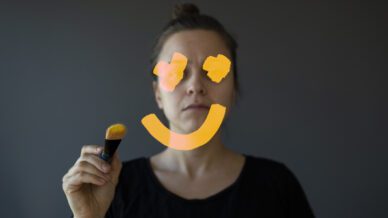 Photo of a woman drawing on a smile to represent phrases that promote toxic positivity