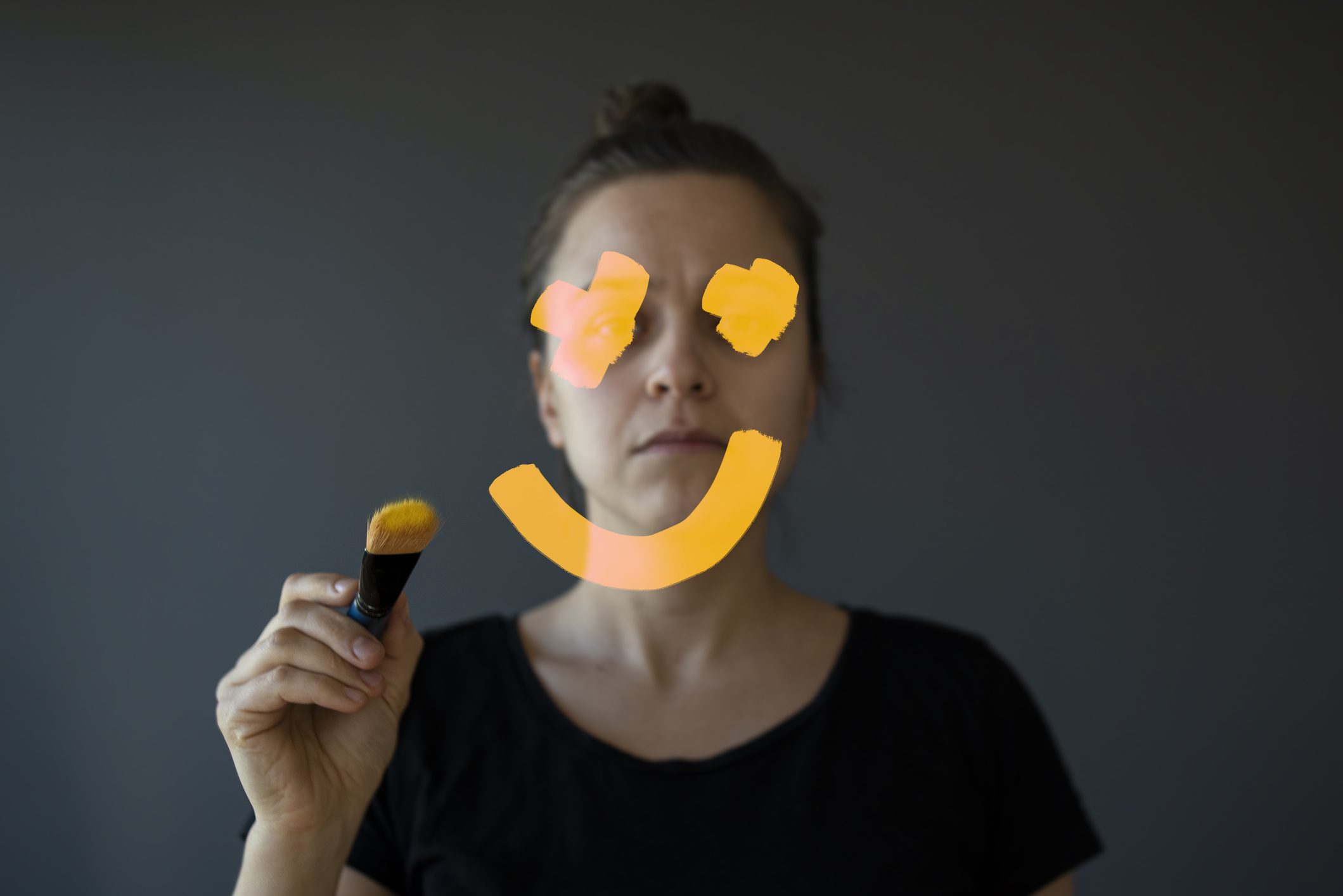 Photo of a woman drawing on a smile to represent phrases that promote toxic positivity