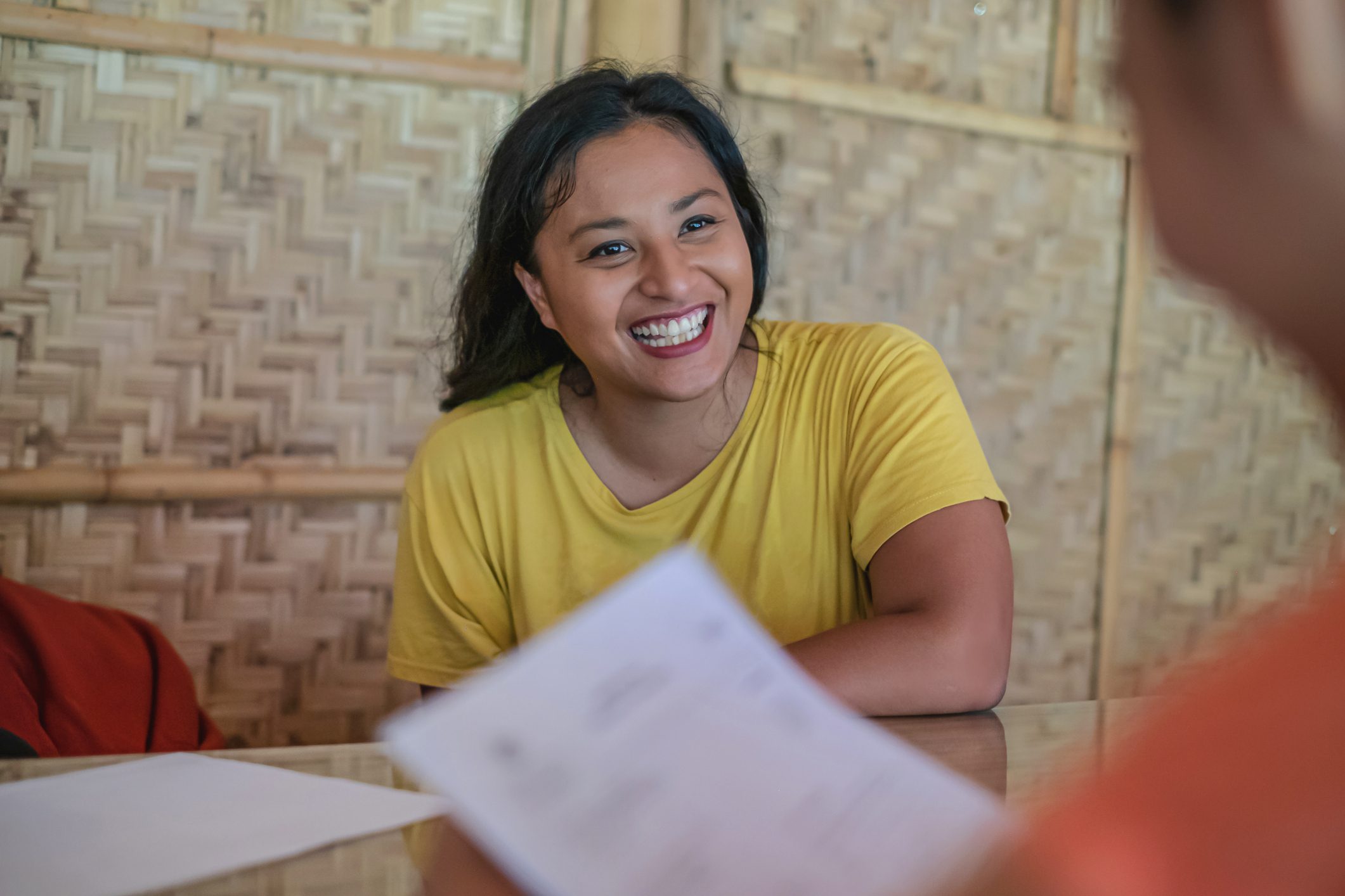 Shot of a confident Malaysian woman having a job interview for a non-profit environmental organization. An unrecognizable human resource manager in front of her is holding her resume.