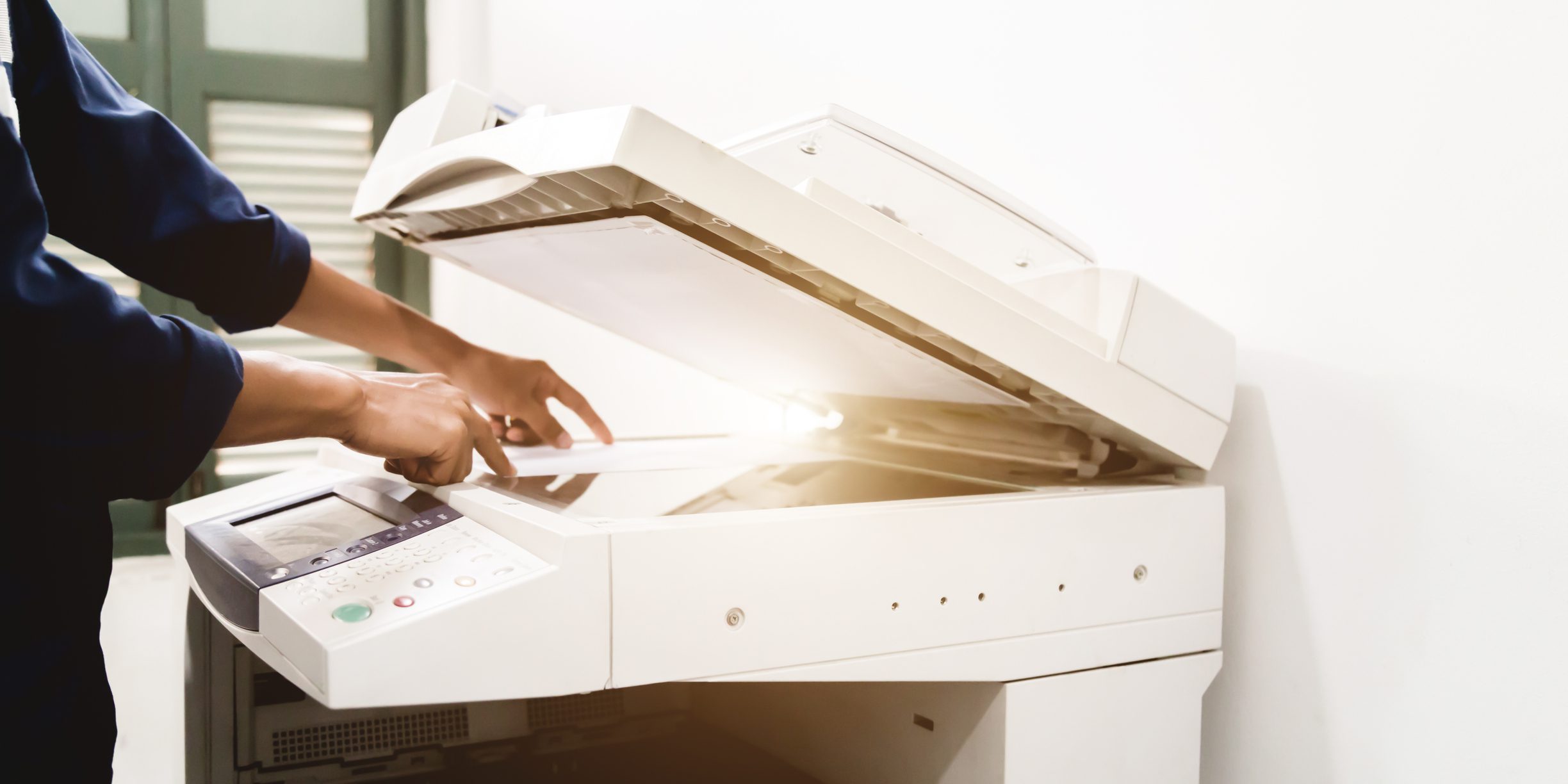 Photo of a photocopier with a person's hands being shown using it