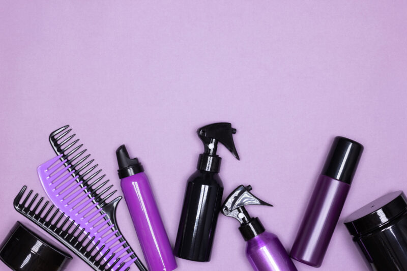 Famous inventors: Hair care and styling products with combs layout on purple background. Copy space