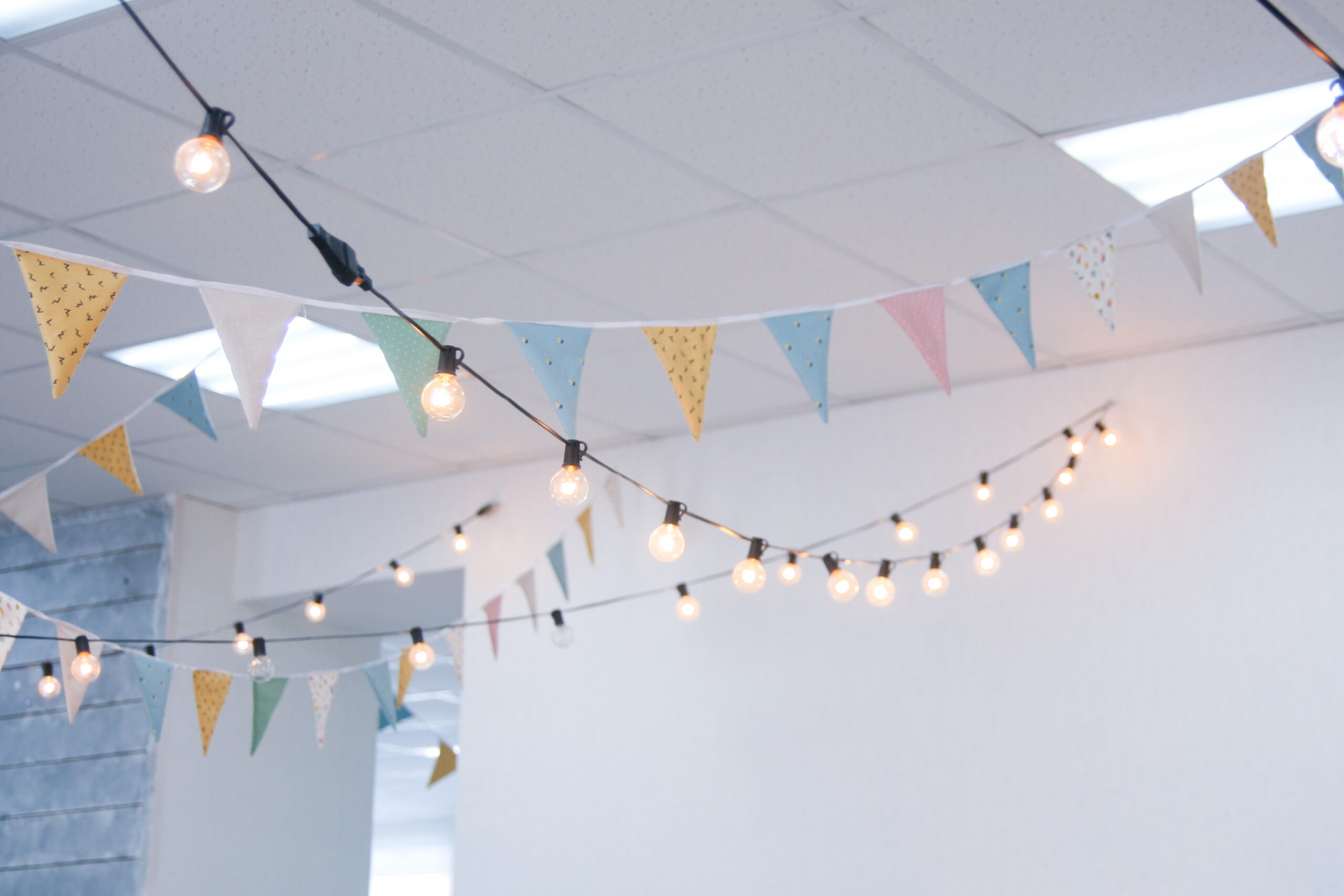 Colorful flags and string lights hanging from a classroom ceiling