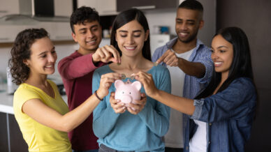 Group of students feeding coins into a piggy bank
