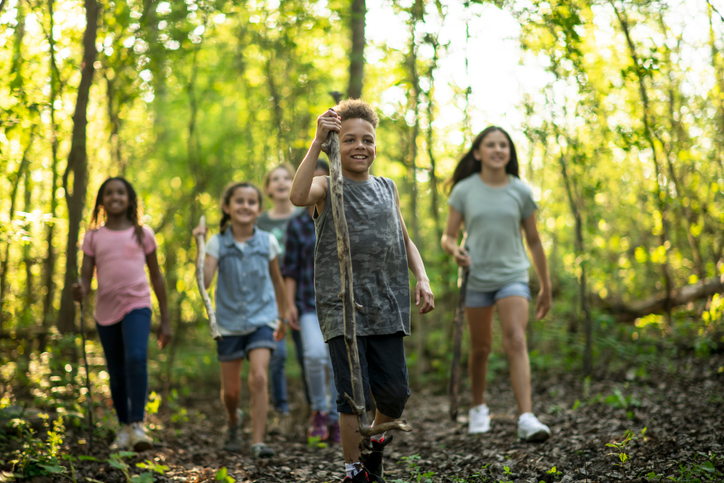 Several kids are seen hiking in nature.