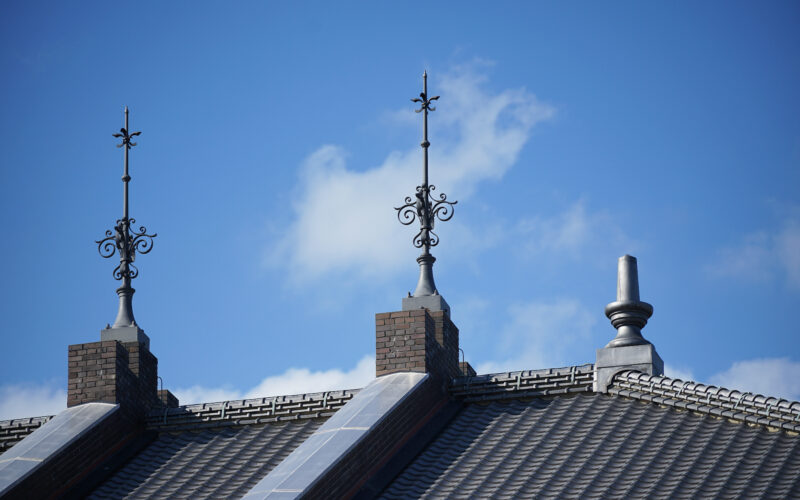 Famous inventors: Lightning rod on roof of building on a clear blue sky day.