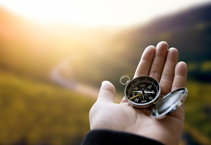 A hand is seen holding an open compass.