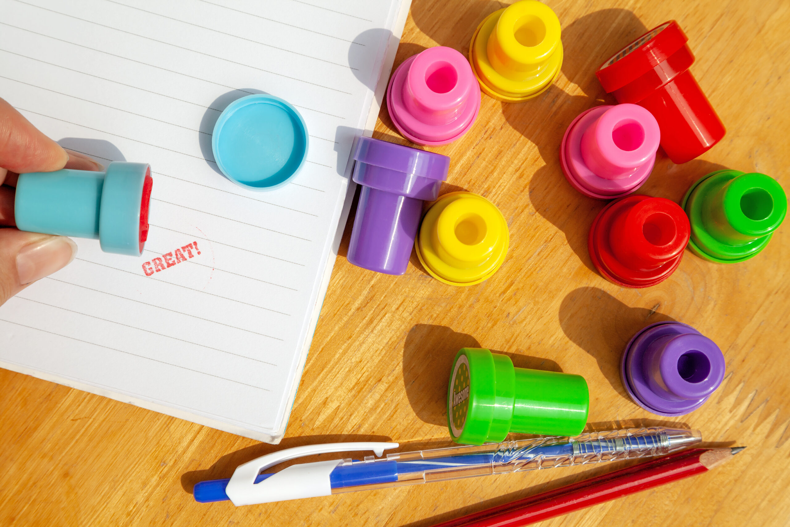 Teacher giving a mark Great for a text or a homework in a notebook using colorful stamps