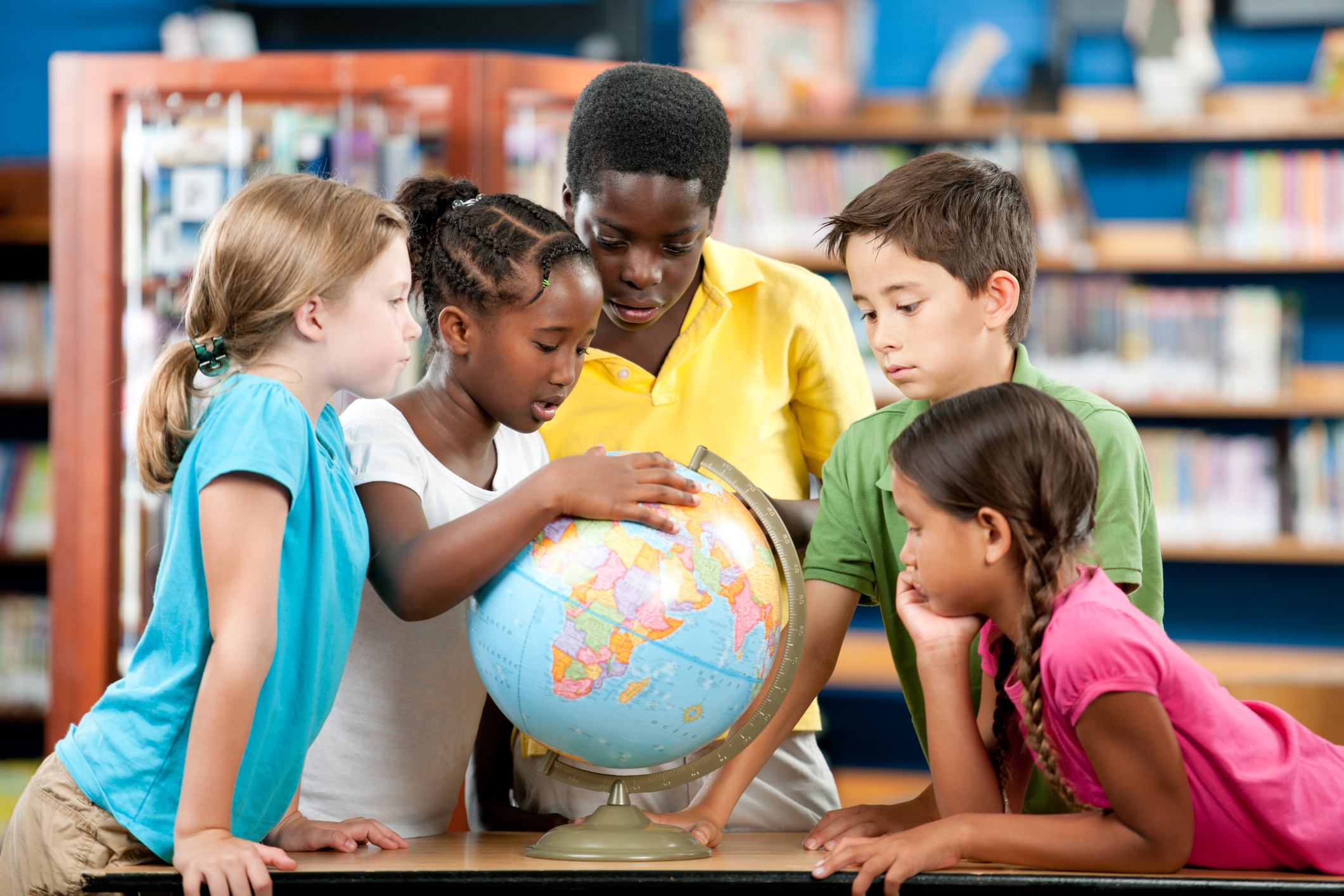 Elementary students looking closely at a globe