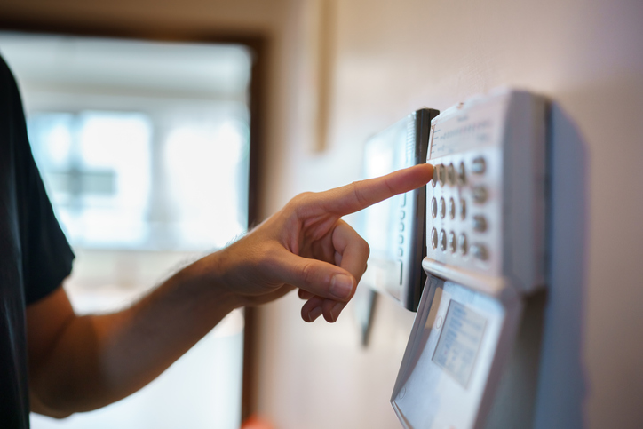 The man is setting up the home alarm system before leaving the house