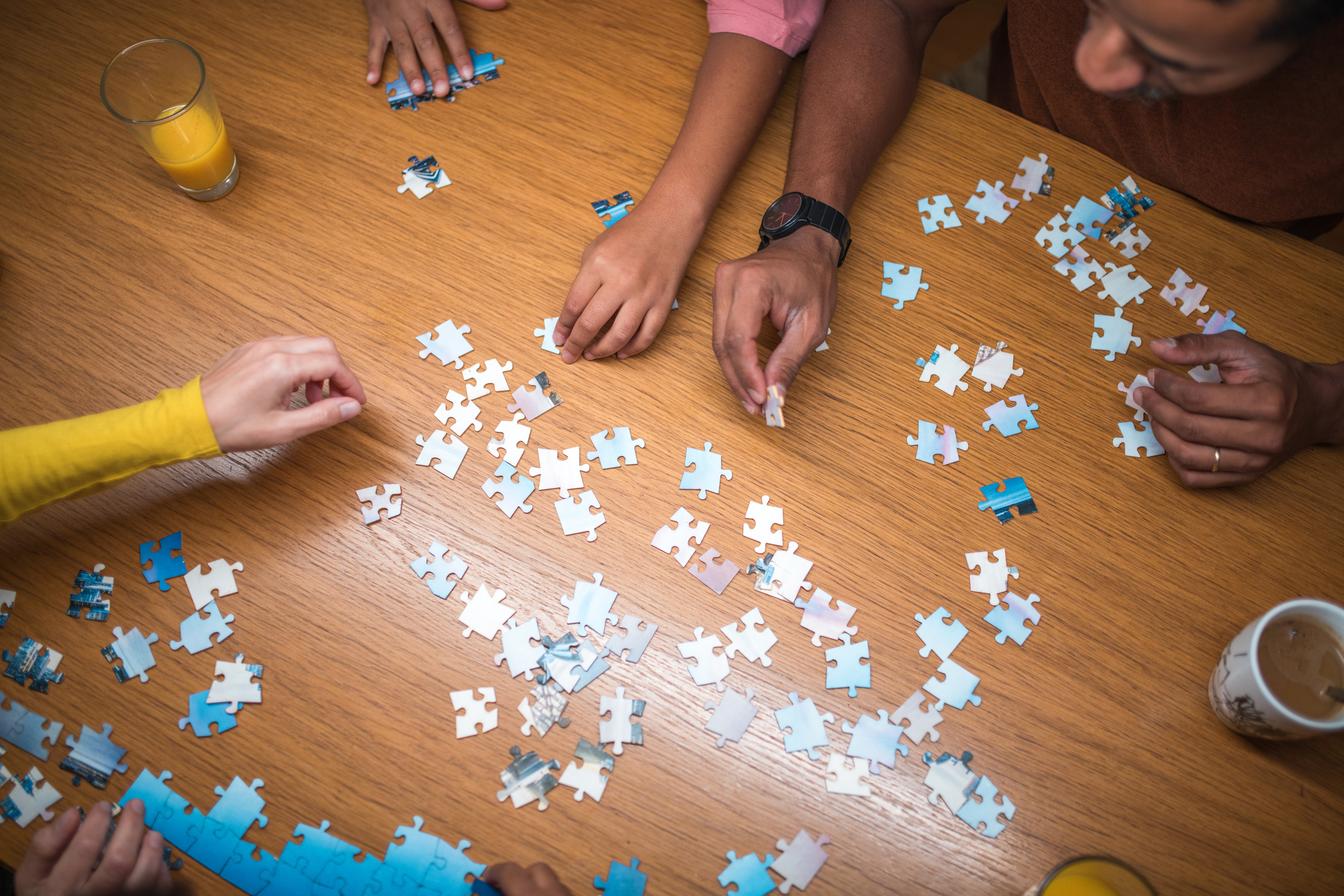 The mixed race family, with two daughters, bonds over puzzles at the dining room table, creating moments of connection and happiness.