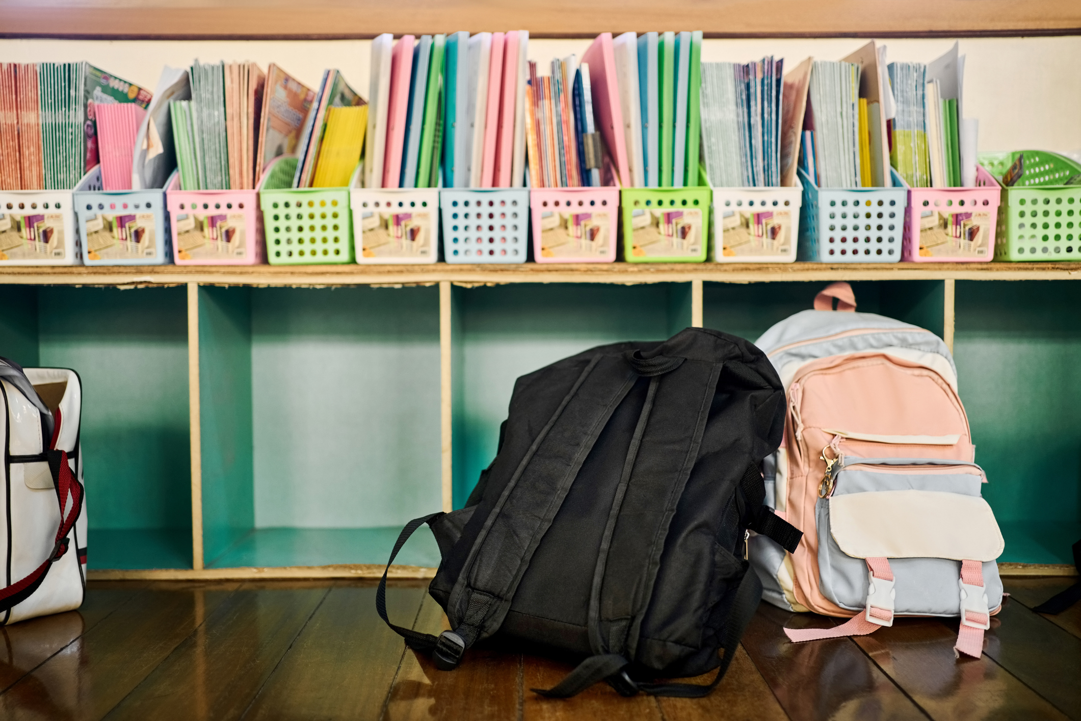 School kids books arranged in boxes over cabinet with schoolbags on floor in primary classroom