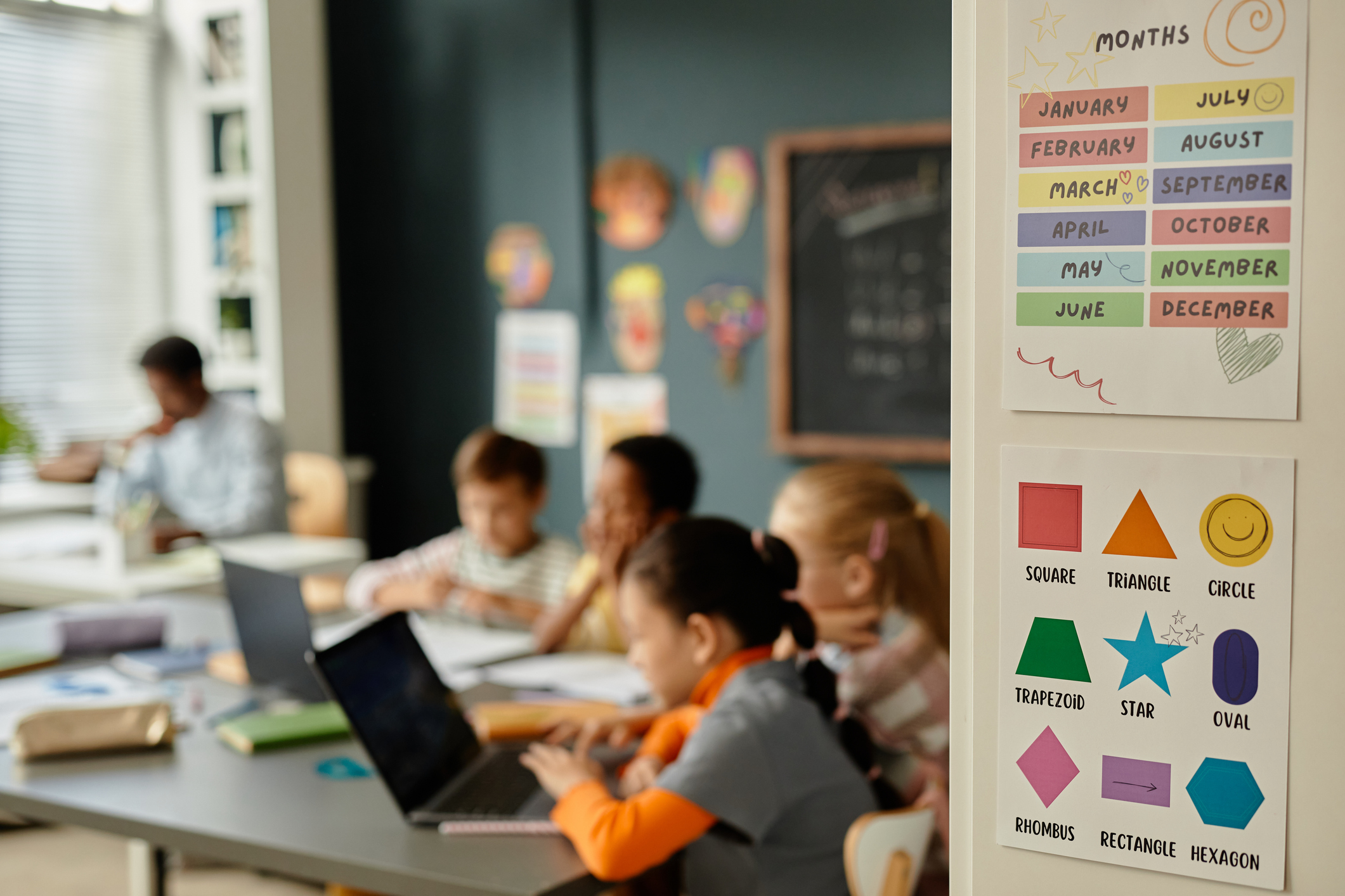 Background shot of educational posters on cupboard with colorful pictures of months of year and different geometric shapes in primary school classroom, copy space