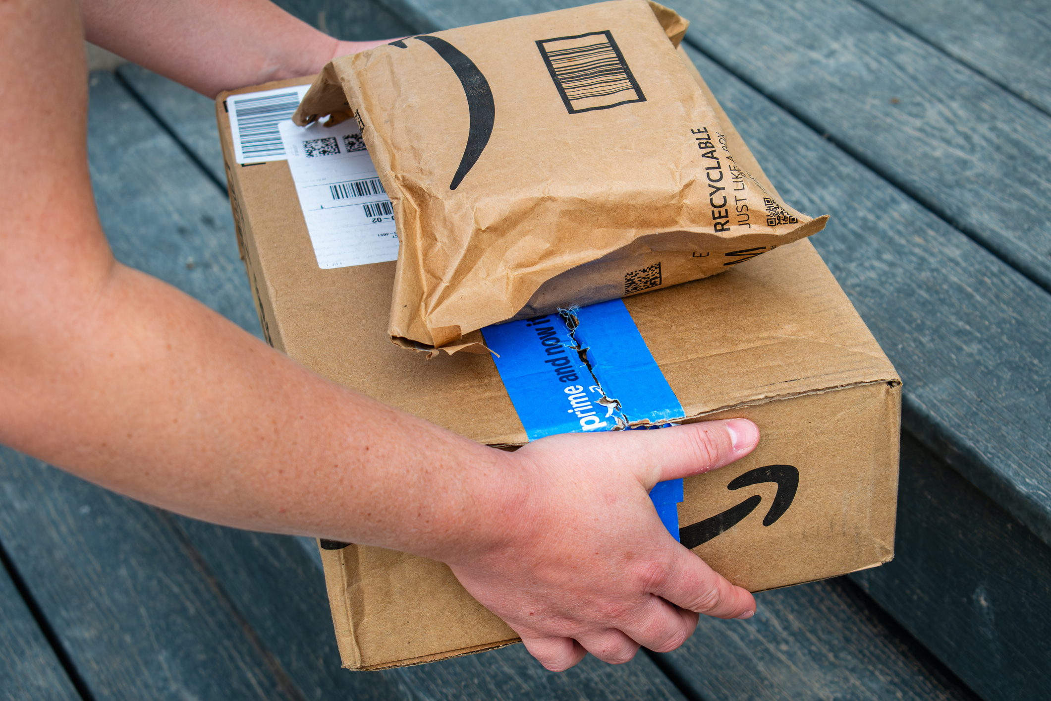 An Amazon delivery worker places Amazon Prime packages on the doorstep of a residence
