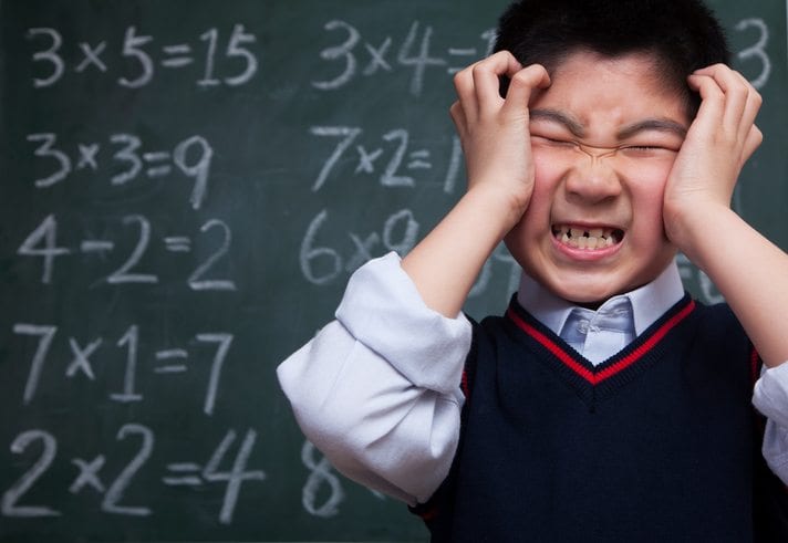 Frustrated schoolboy in front of blackboard with math problems