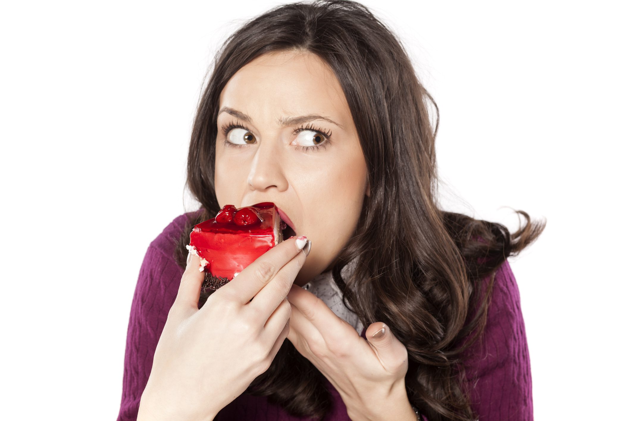 A woman eating a strawberry cake looking guilty