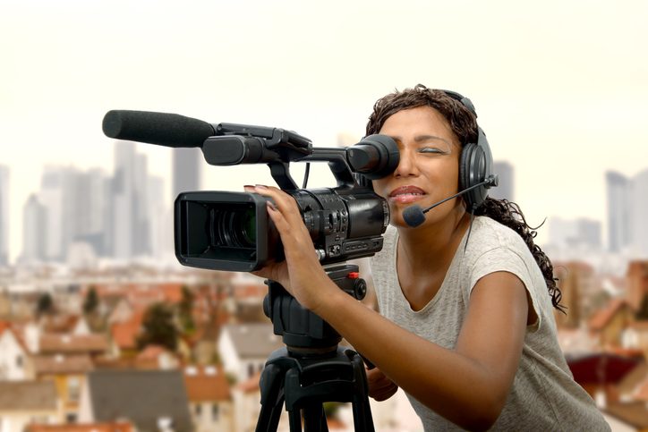 A woman is shown looking through a large video camera (art careers)