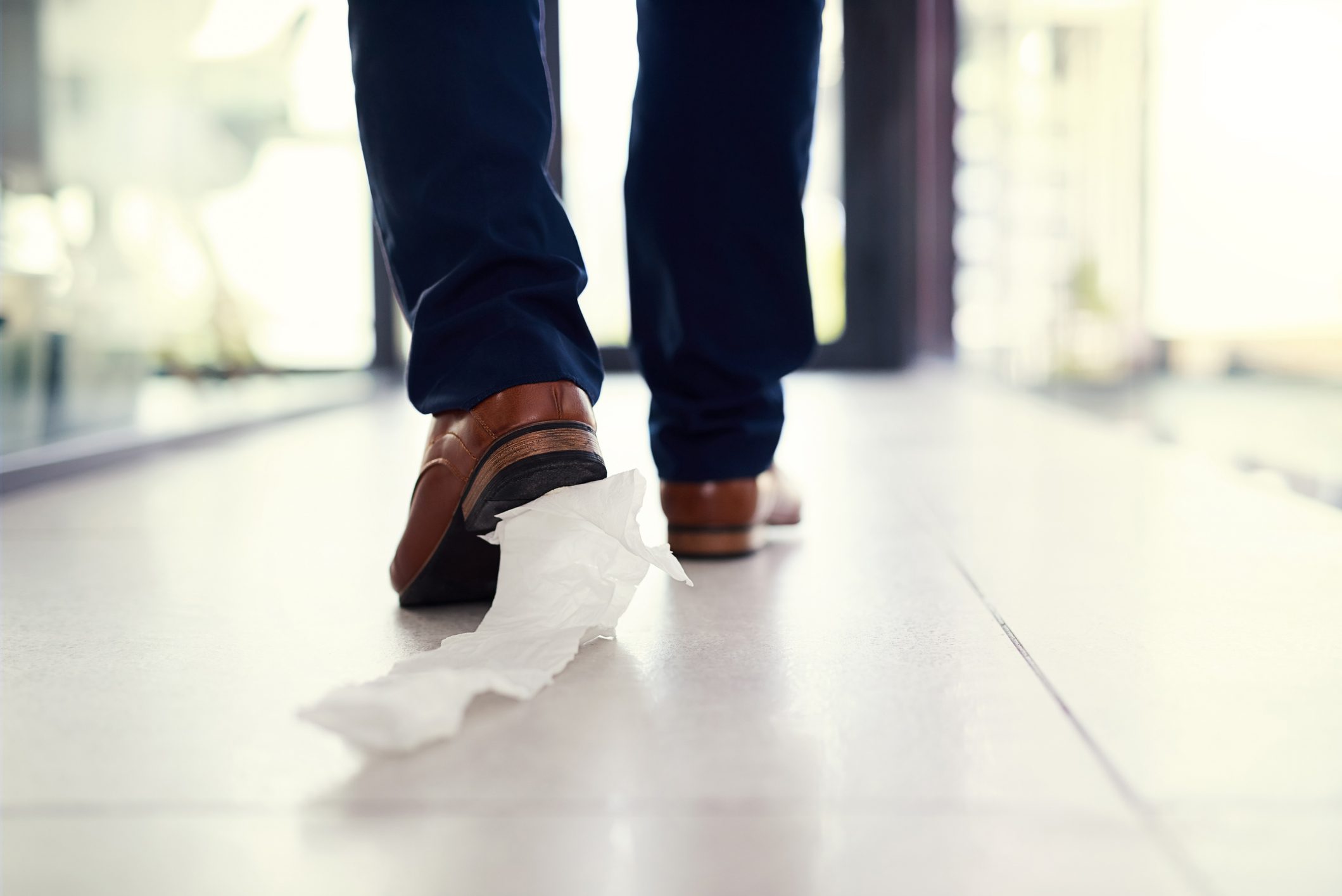 Closeup shot of a businessman walking in an office with toilet paper stuck to his shoe