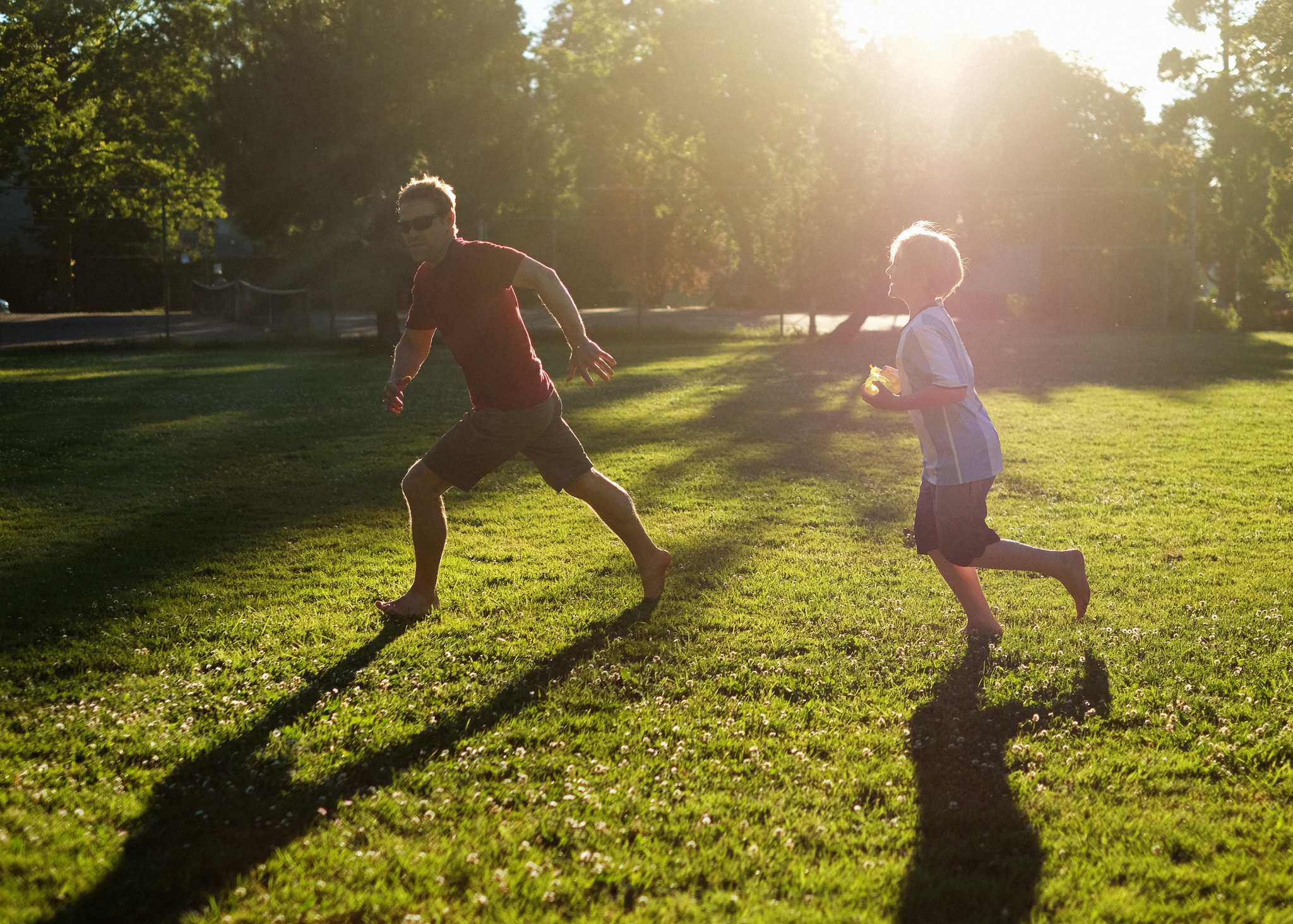 A man and a child are shown chasing their shadows outside (tag games)
