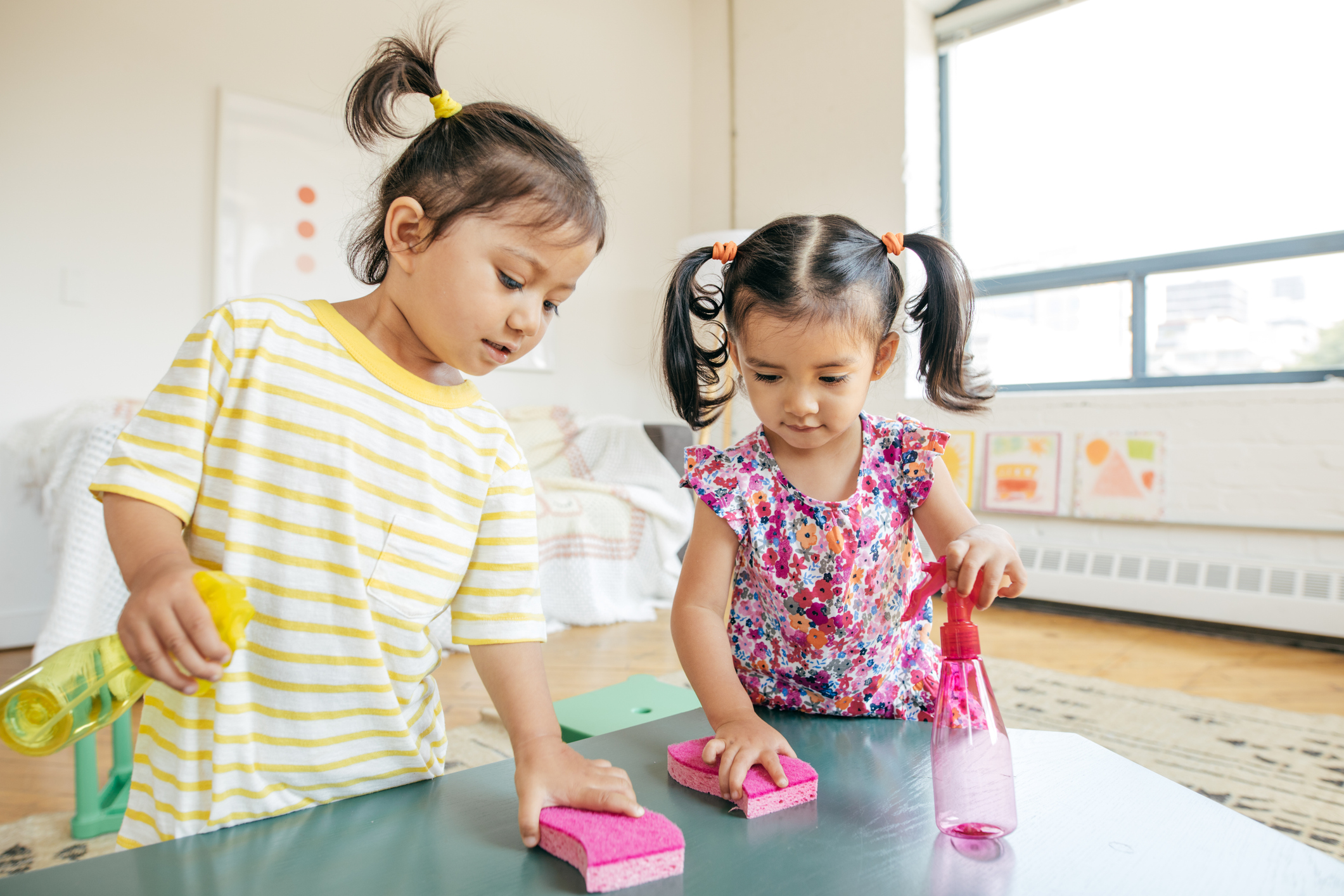 Two children using sponges to clean a classroom table