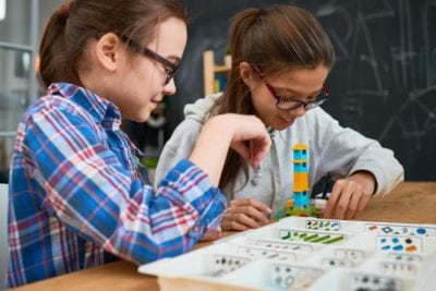 Girl students making tower from building blocks - STEAM Education Makes Our Students Better Risk-Takers. Here’s Why.
