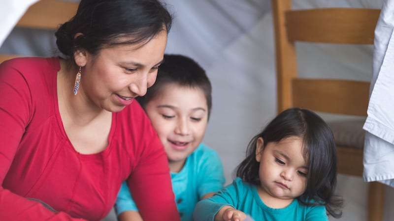 Native American mom reads with her son under makeshift fort in living room